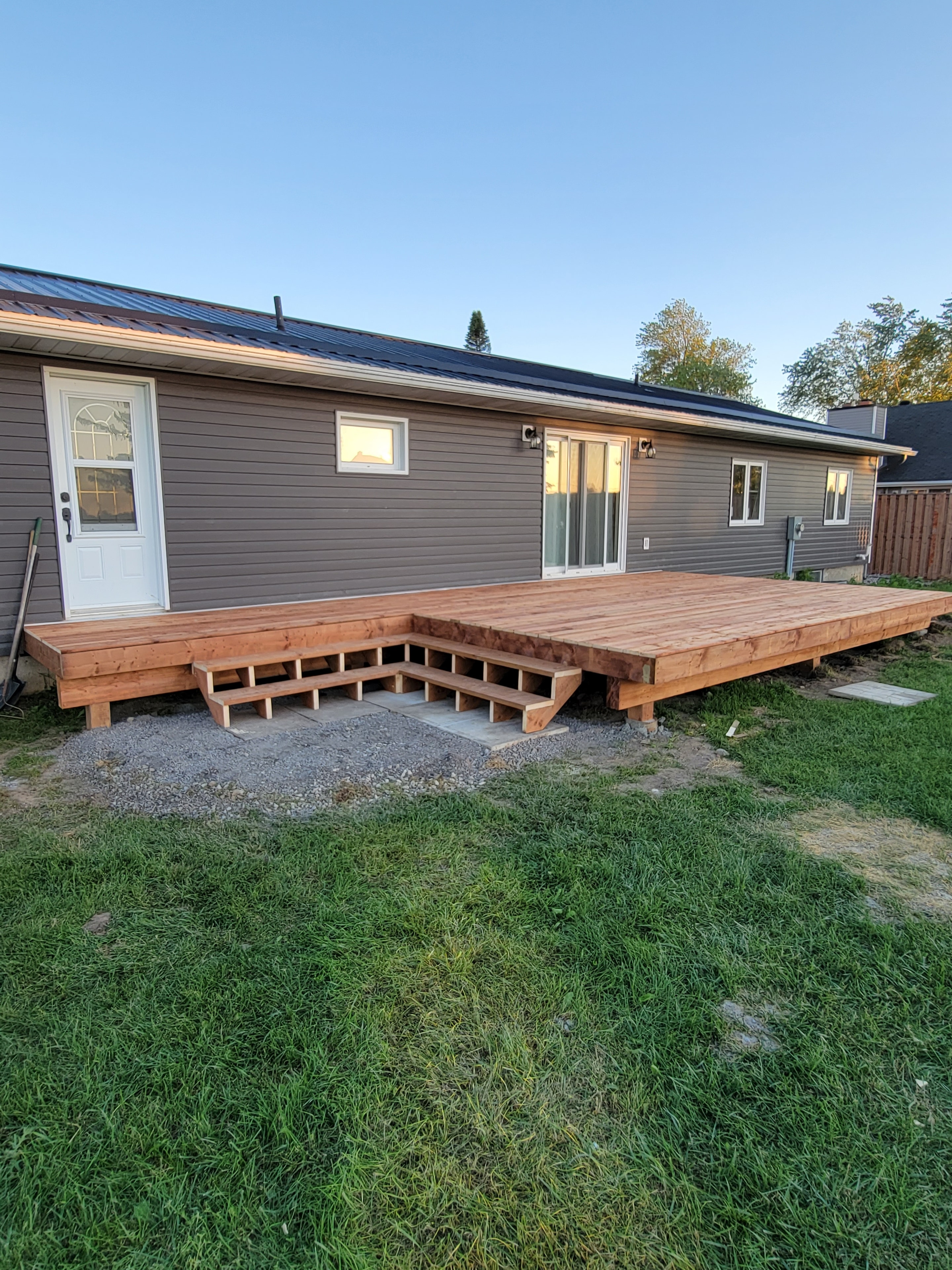 Residential exterior with dark metal siding and new wood deck under construction